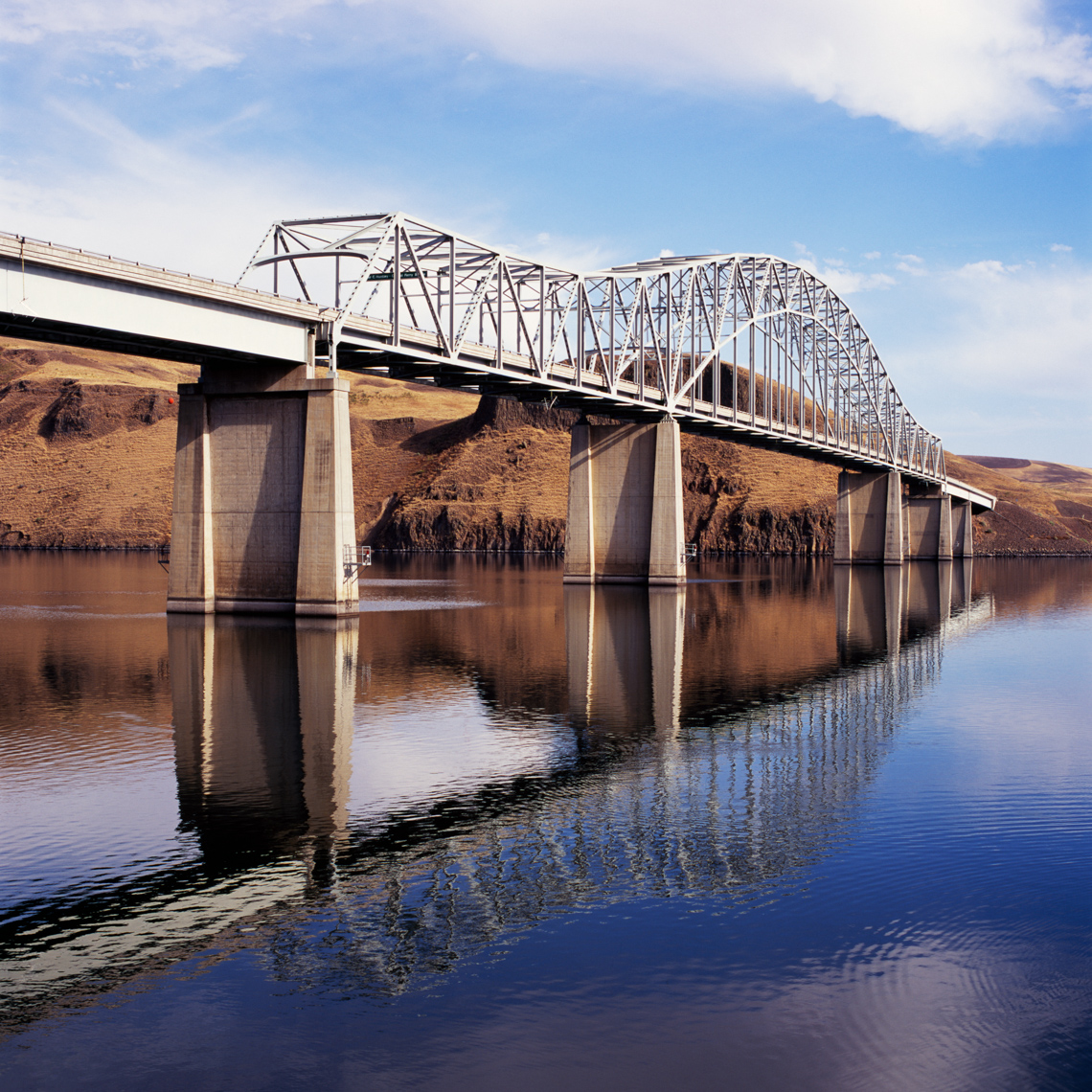 Steel and concrete highway bridge over river. Transportation engineering construction industry.