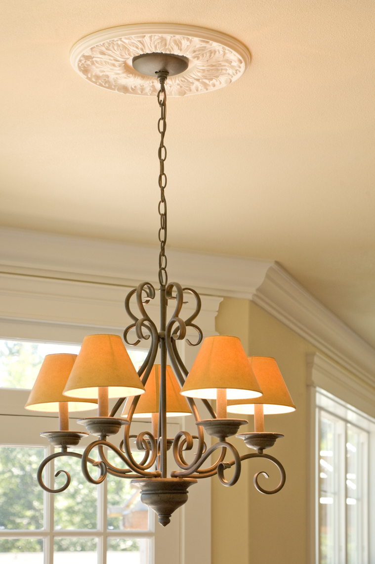 Chandelier hanging from ceiling in traditional home with windows in background