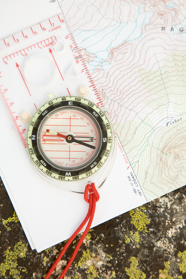 Topographic map and compass on lichen-covered boulder