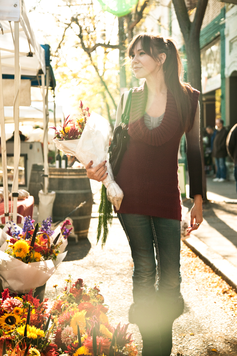 Young Hispanic woman with flowers walking at Farmers
