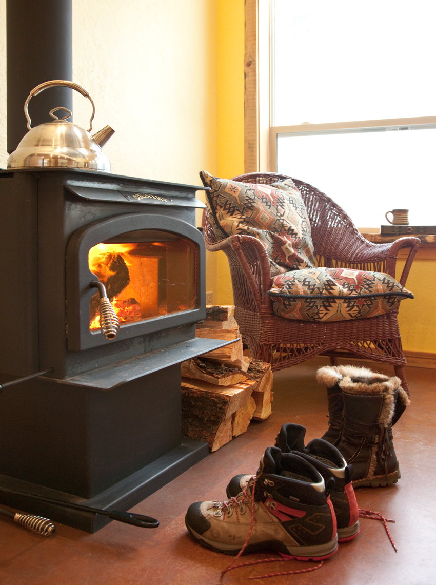 Cabin interior with wood burning stove, chair and boots. Winter vacation getaway.