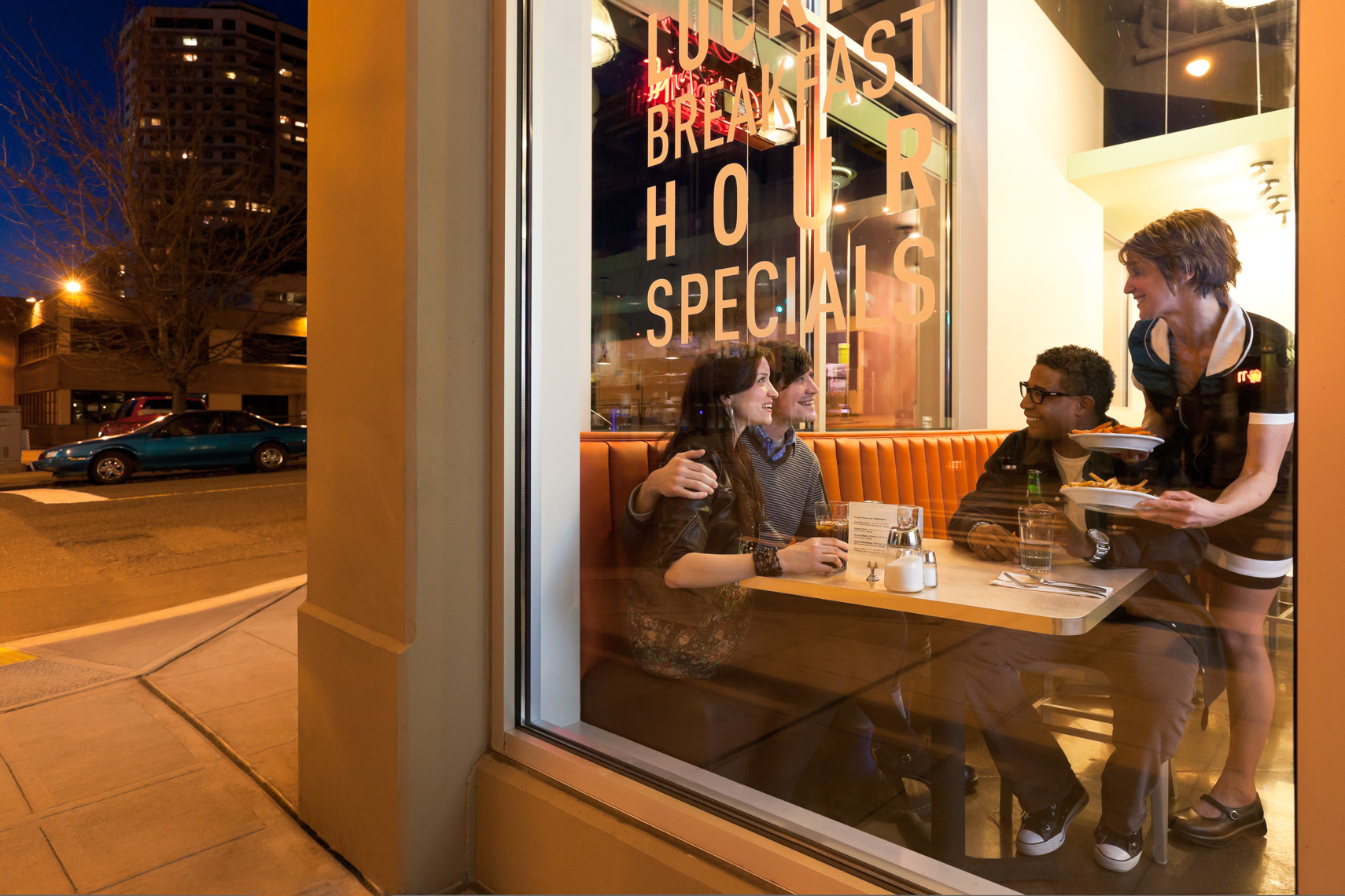 Waitress serving multiethnic group of friends customers dining out in cafe diner restaurant