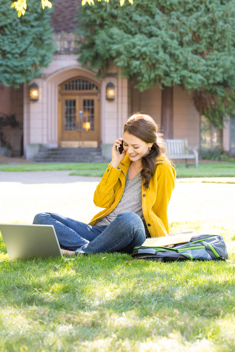 College student using laptop and cell phone on university campus