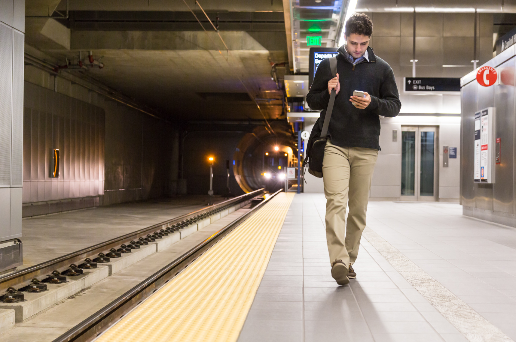 Young professional man with cell phone on subway platform. Mobile technology shoot.